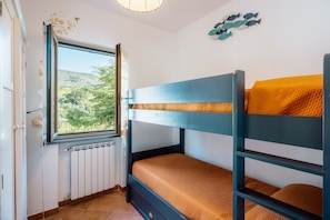 A bunk bed room with a window, radiator, and decorative wall art.