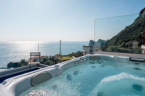 A hot tub with a view of the sea and a mountainous landscape.