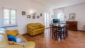 Un salon avec un canapé jaune, une table à manger avec des chaises et un téléviseur.