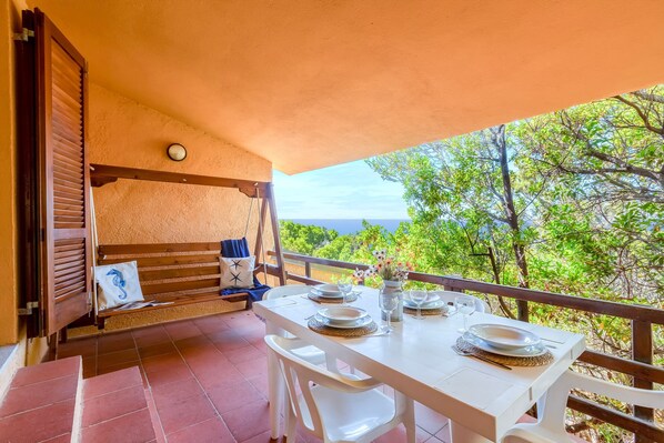 Un balcon avec une table dressée pour le dîner, un canapé et une vue sur la mer.