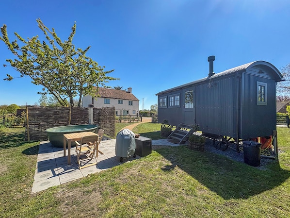 A house with a hot tub, a small shed, and a tree in the yard.
