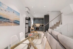 Um interior moderno com área de jantar, cozinha e escada.