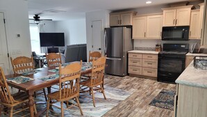 A modern kitchen with wooden cabinets, stainless steel appliances, and a dining area with a wooden table and chairs.