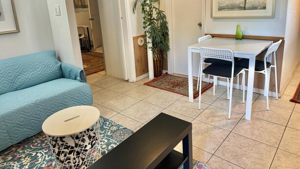 A living room with a blue sofa, a small round table, and a dining area with a white table and chairs. - Charming 1-bedroom beautifully furnished apartment in quaint Roslyn w/Parking (Roslyn)