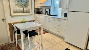 A compact kitchen with white cabinets, a dining table, and a refrigerator. - Charming 1-bedroom beautifully furnished apartment in quaint Roslyn w/Parking (Roslyn)