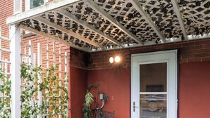 A patio with a table and chairs, a white door, and a brick wall. - Charming 1-bedroom beautifully furnished apartment in quaint Roslyn w/Parking (Roslyn)