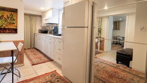 A modern kitchen with white cabinets, a refrigerator, and a dining area with a table and chairs. - Charming 1-bedroom beautifully furnished apartment in quaint Roslyn w/Parking (Roslyn)