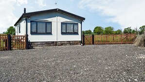A single-story house with a sloped roof, two windows with shutters, a chimney, and a gravel driveway. - 1 bedroom accommodation in Northampton (Northampton)