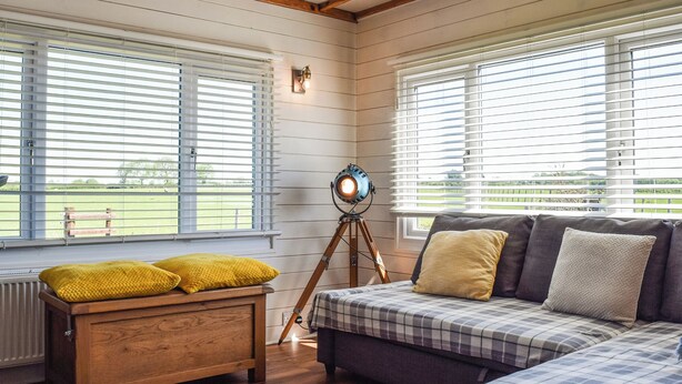 A cozy room with wooden floors, a sofa with plaid bedding, and a bench with yellow cushions. - 1 bedroom accommodation in Northampton (Northampton)