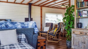 A cozy cabin interior with a sofa, chairs, a bookshelf, and a fireplace. - 1 bedroom accommodation in Northampton (Northampton)
