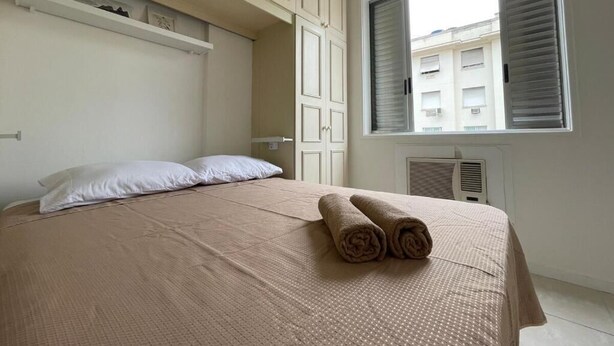 A bedroom with a bed, pillows, a window, and a radiator.