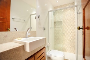 Un baño con lavamanos, espejo, inodoro y cabina de ducha.