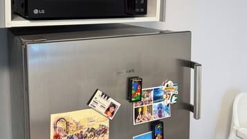 Una cocina con un microondas negro en la repisa superior y un refrigerador de acero inoxidable debajo.