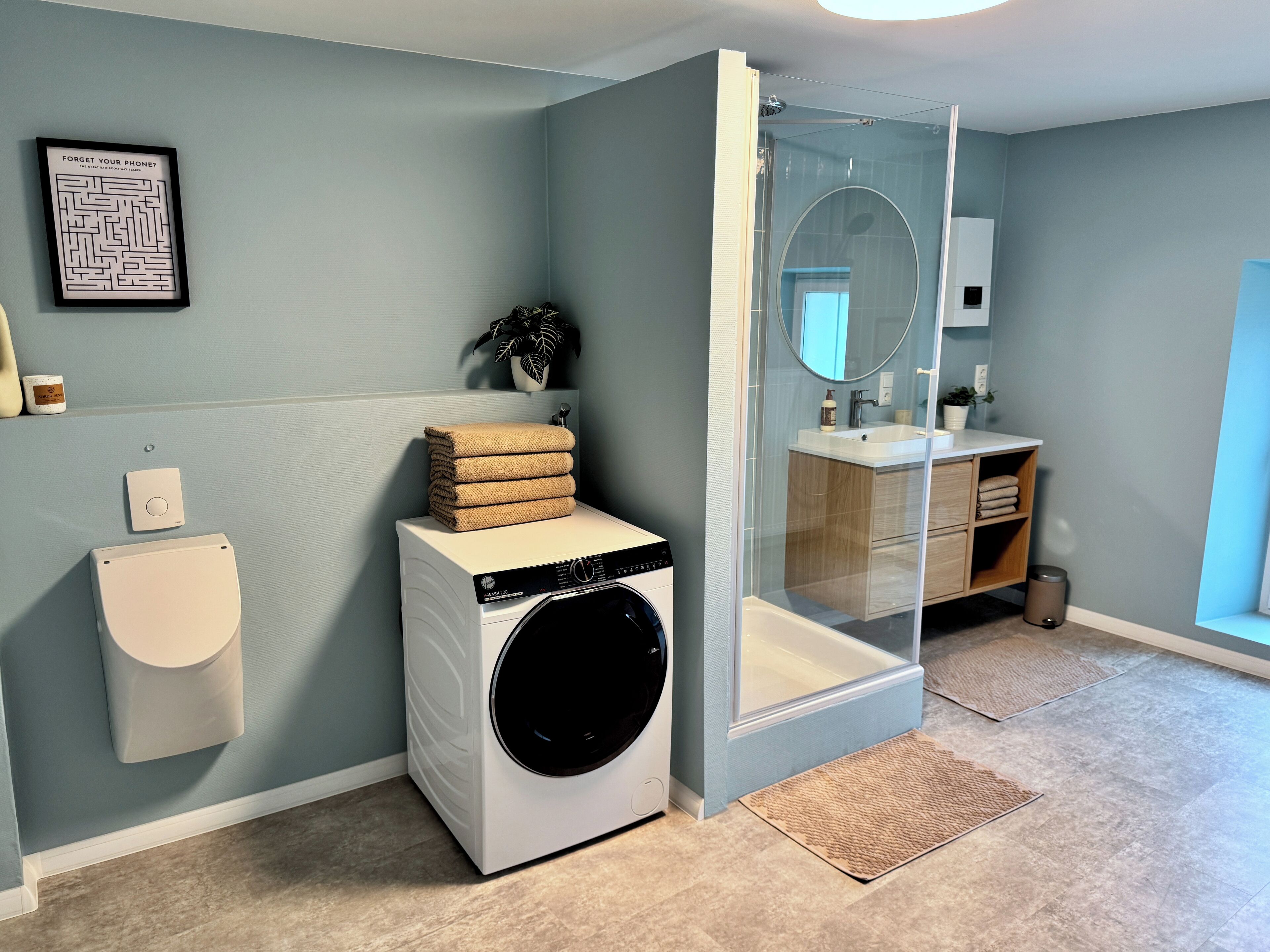 Ein modernes Badezimmer mit Waschmaschine, Toilette und einer Duschkabine.