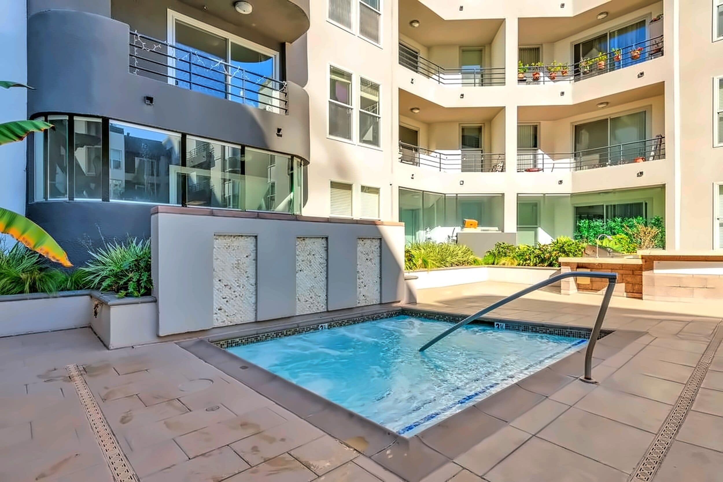 A modern building with a swimming pool, balconies, and outdoor plants.