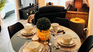 A dining area with a round table set for four, surrounded by black chairs. A potted plant is in the center, and a television is mounted on the wall. - Luxury 1BR Condo | Sophisticated & Stylish Stay by Square One (Mississauga)