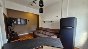 A compact kitchen with a black countertop, a brown sofa, and a black refrigerator. - SUH Copacabana 89 Beach View (Rio de Janeiro)