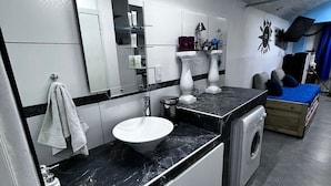 A modern bathroom with a sink, mirror, and a washing machine. - Winewalker walks to the cellars, pool, patio and garage. (Luján de Cuyo)