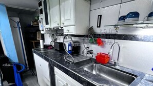 A kitchen with white cabinets, a black countertop, and a stainless steel sink. - Winewalker walks to the cellars, pool, patio and garage. (Luján de Cuyo)