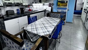 A compact kitchen with white cabinets, a microwave, and a sink. There is a dining table with a checkered tablecloth and blue chairs. - Winewalker walks to the cellars, pool, patio and garage. (Luján de Cuyo)