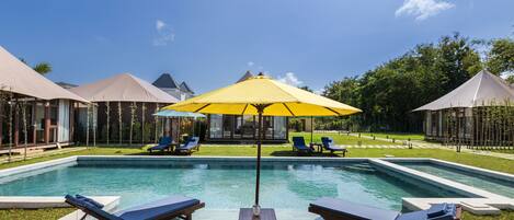 Alberca al aire libre, sombrillas en la alberca y camastros