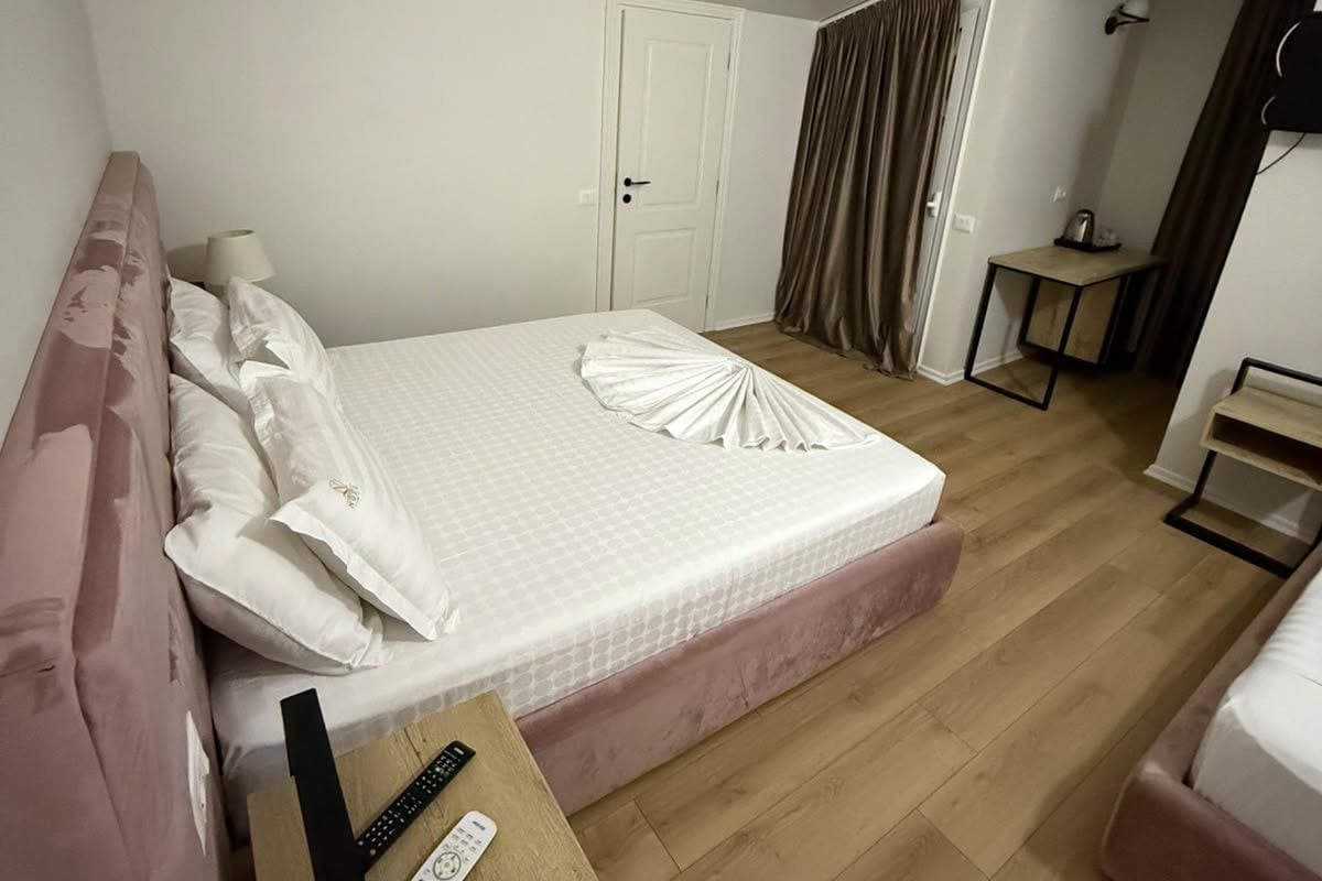 Een hotelkamer met een bed, nachtkastje en een klein bureau met een stoel.