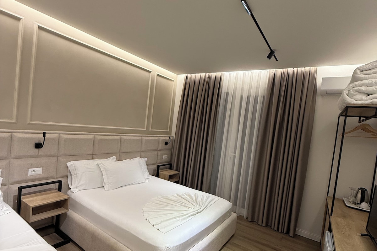 Een moderne hotelkamer met een groot bed, nachtkastjes, een bureau en een kledingkast.