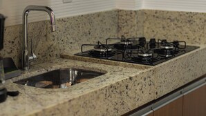A kitchen with a granite countertop, stainless steel sink, and a gas stove. - SUH Copacabana 76  (Rio de Janeiro)