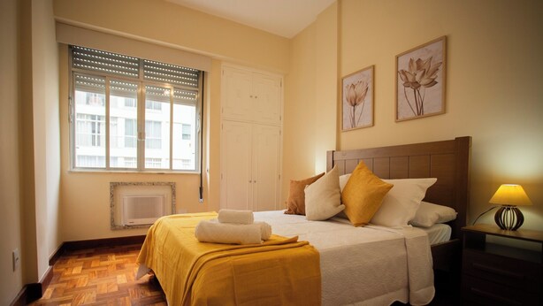 A neatly arranged bedroom with a bed, bedside table, and a window with blinds. - SUH Copacabana 76  (Rio de Janeiro)