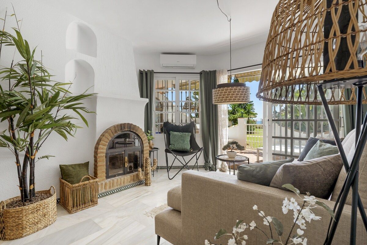 A modern living room with a fireplace, a sofa, a chair, and a large window with a view.