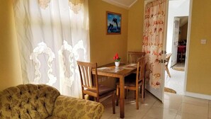 Una sala de estar con un sofá, una mesa de comedor con sillas y un cuadro en la pared.