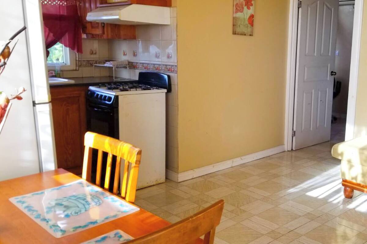 Une cuisine compacte équipée d’une cuisinière, d’une table à manger avec des chaises et d’un canapé dans l’espace salon.
