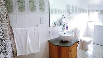 A bathroom with a white sink, wooden cabinet, and a large mirror.