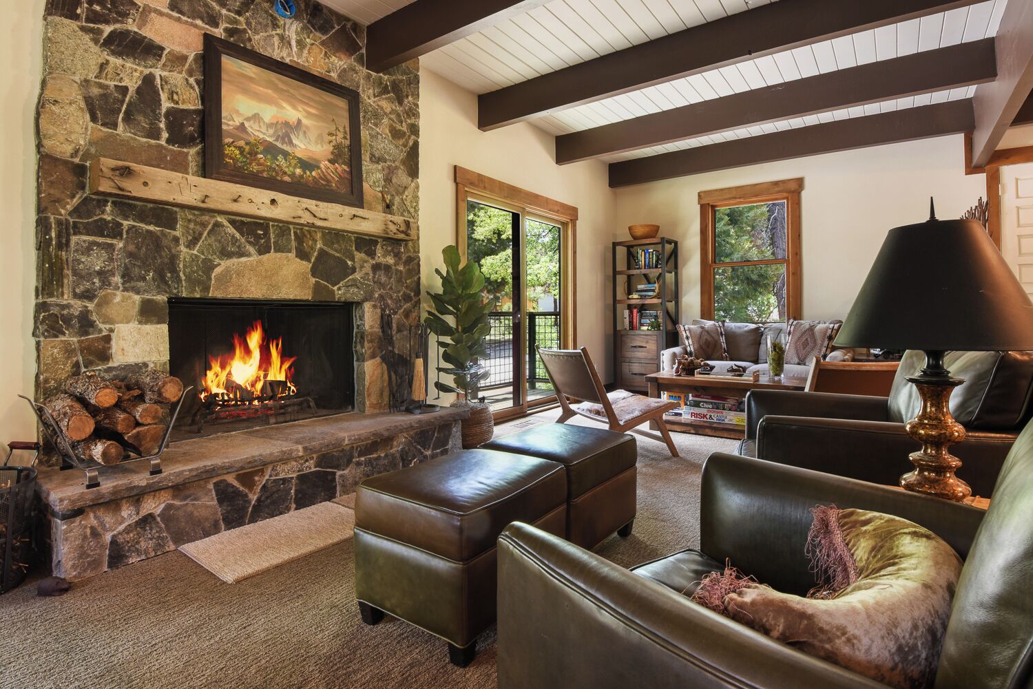 Un salón acogedor con chimenea de piedra, muebles de cuero y una estantería.