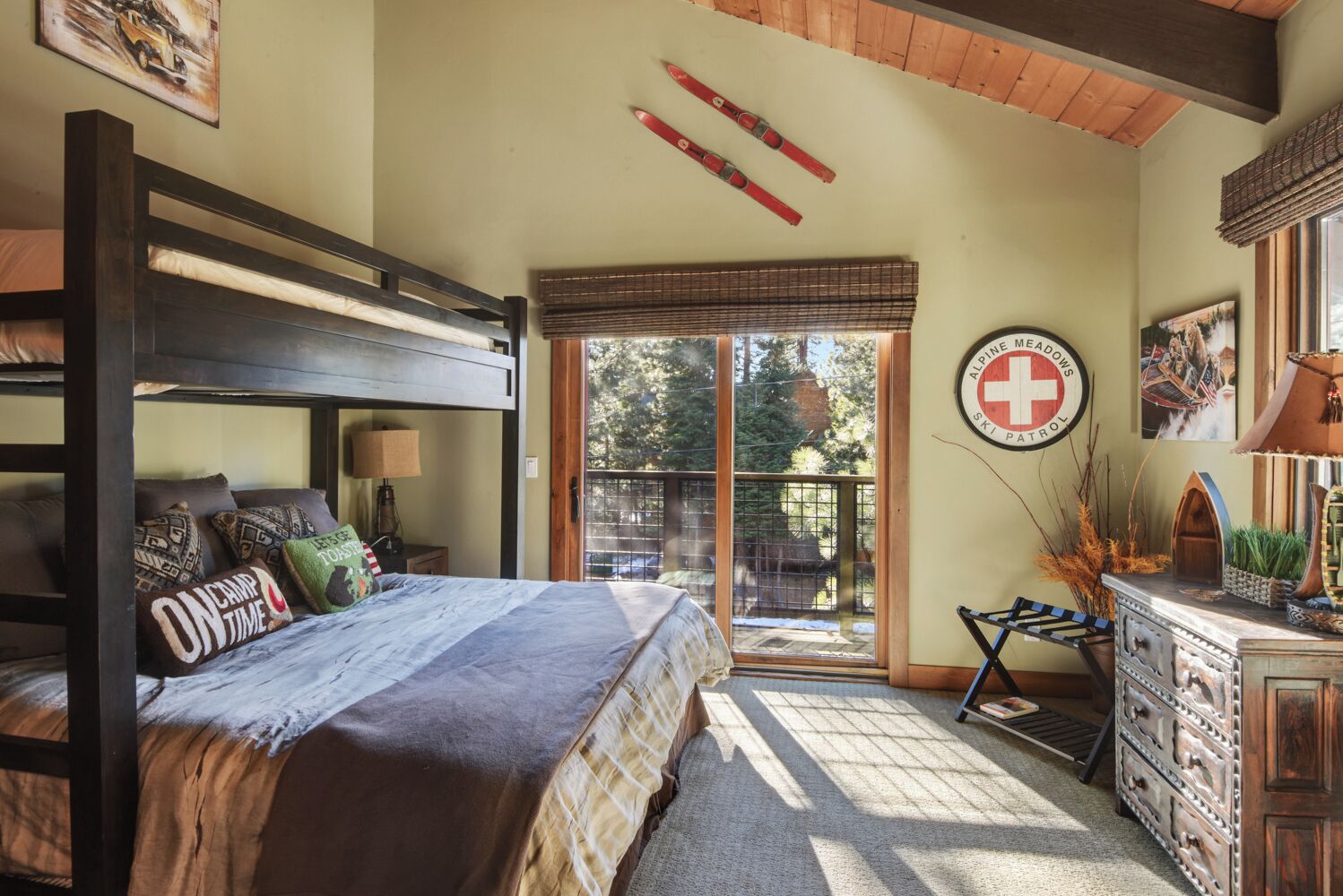 A cozy bedroom with a bunk bed, a desk, and a window overlooking a deck.