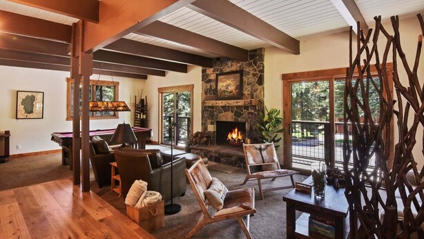 A cozy living room with a stone fireplace, wooden beams, and a pool table. - Kingswood Luxury Home with Hot Tub, Backs to Forest (Kings Beach)