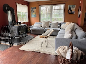 A cozy living room with a fireplace, a grey sofa, a wooden bench, and a wicker basket with towels. - Chimney Hill Charmer for Four Seasons of Fun! (Wilmington)