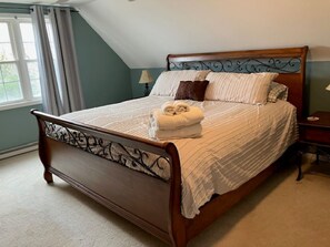Un dormitorio con cama de madera, una ventana con cortinas y una mesita de noche.