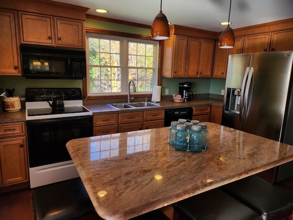 A kitchen with wooden cabinets, a stainless steel refrigerator, a built-in oven, and a granite countertop. - Chimney Hill Charmer for Four Seasons of Fun! (Wilmington)