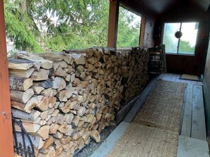 A covered outdoor area with a stack of firewood and a woven mat on the floor. - Chimney Hill Charmer for Four Seasons of Fun! (Wilmington)