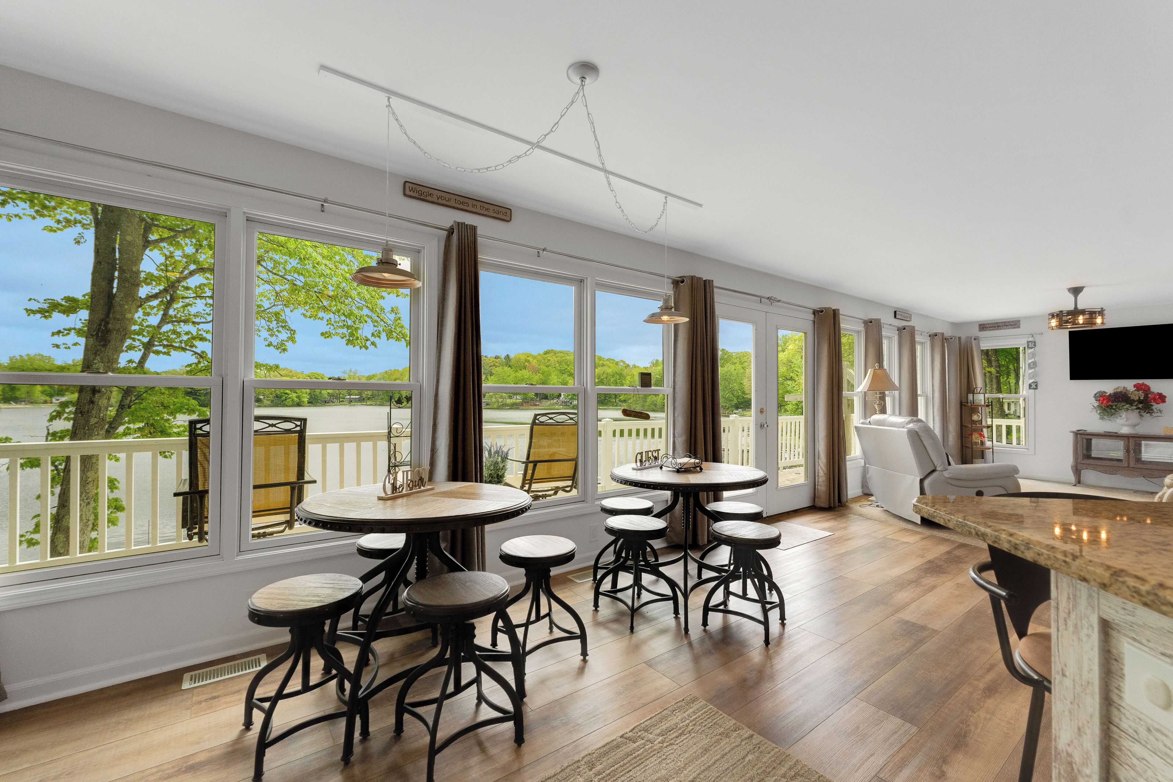 A spacious kitchen with large windows, a dining area with bar stools, and a view of a lake.