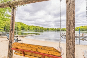 Et legesæt i træ over en sandstrand med en sø og en bro i baggrunden.