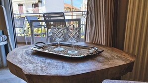 A wooden table with a tray holding three glassware items, a chair, and a view of a balcony with outdoor furniture. - Kainon Asti (Lefkada)