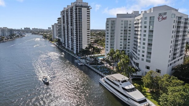 Un hotel frente al río, con un gran edificio blanco que dice "Gallery One", un barco amarrado en el muelle y un río con una embarcación en movimiento.