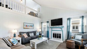 A living room with a sofa, a coffee table, a fireplace, and a TV. - The Salty Rooster by Brunswick Vacation Rentals: New Pool & Renovated Bedrooms (Ocean Isle Beach)