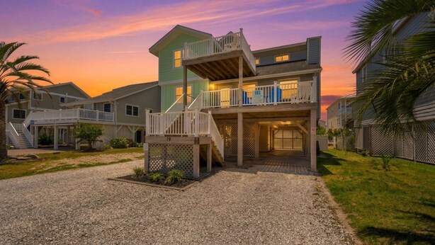 A multi-story residential building with a covered porch, a staircase, and a driveway. - The Salty Rooster by Brunswick Vacation Rentals: New Pool & Renovated Bedrooms (Ocean Isle Beach)