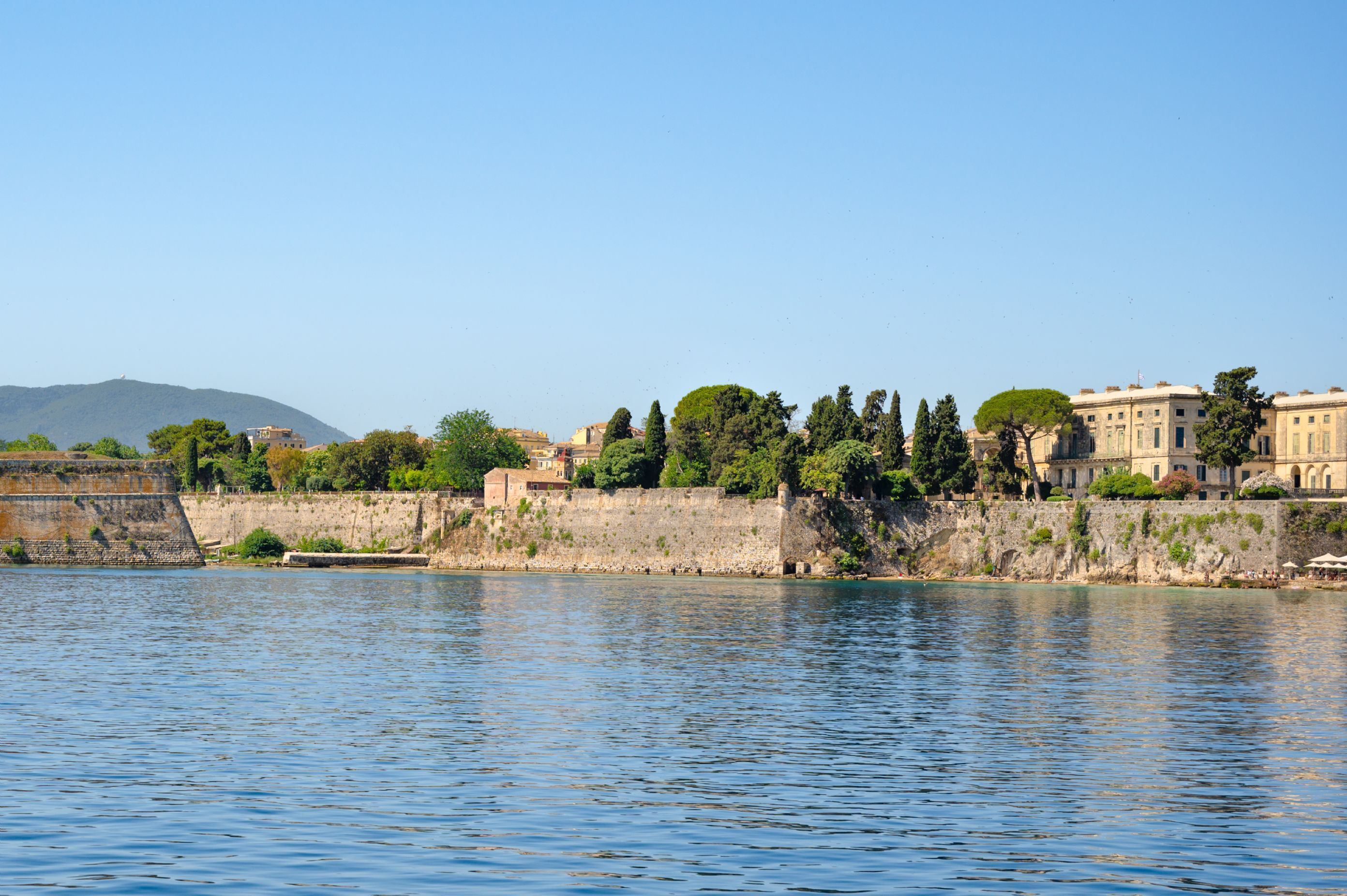 Una vista sul lungomare con un muro di pietra, edifici e alberi.