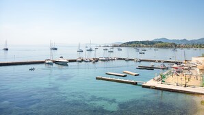 A marina with boats docked, clear water, and a hilly landscape in the background. - Anthia: Balcony and BBQ, 3 min to Airport, WiFi, Aircon (Kanoni)