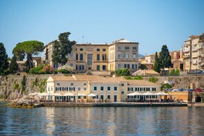 Un edificio frente al mar con varios balcones, una terraza con asientos al aire libre y vistas al océano.