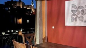 Un comedor con una mesa y sillas de madera, una pared roja y vistas a edificios por la noche.